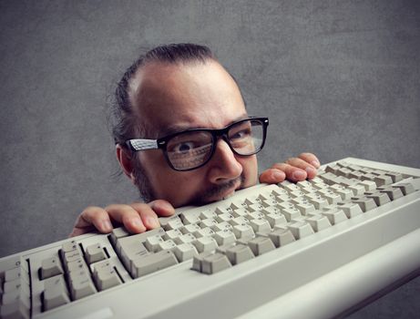 Eccentric angry man bites a keyboard