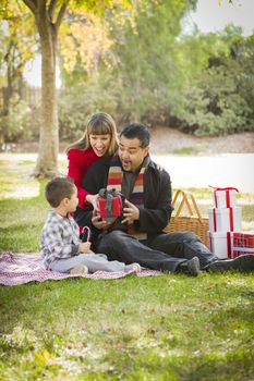 Young Mixed Race Family Enjoying Christmas Gifts in the Park Together.