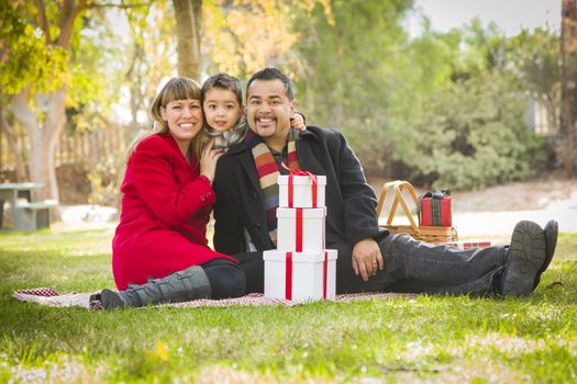 Young Mixed Race Family Enjoying Christmas Gifts in the Park Together.