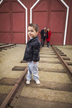 Young Adorable Mixed Race Boy at Train Depot with Parents Smiling Behind.