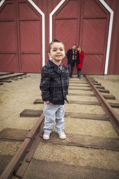 Young Adorable Mixed Race Boy at Train Depot with Parents Smiling Behind.