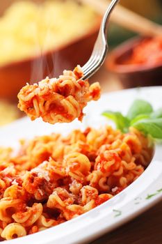 fork holds pasta bolognese, close up shot