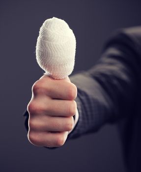 A close up of a  bandaged thumb up
