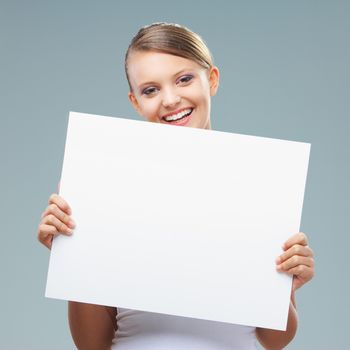 Happy blonde girl holding up a blank banner, copy space