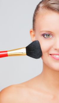 Cropped view of a young woman having blusher applied to her cheeks 