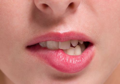 mouth closeup of a woman bites on her lips