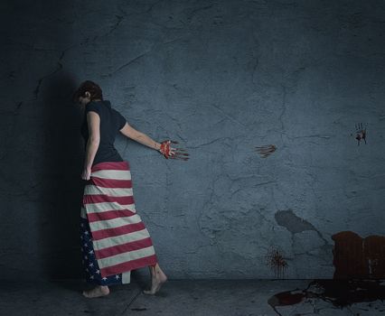 young woman at a grey wall wearing american flag with a blood trail behind her
