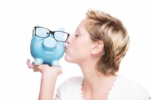 young blonde woman kissing a blue piggy bank on white background