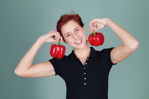 happy redhead woman holding two red pepper bells
