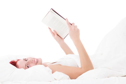 happy redhead woman in bed reading a book on white background