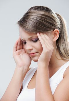 An attractive young woman with her eyes closed is rubbing at her temples to relieve a headache