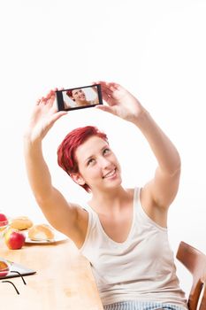 blonde happy woman at breakfast making a self portrait with her smartphone on white background