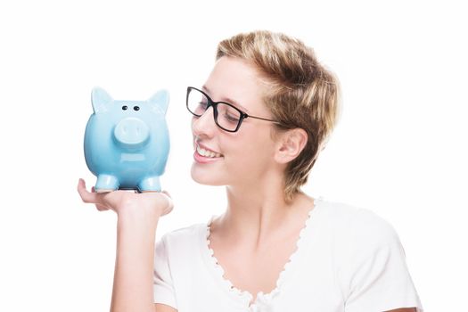 blonde beautiful woman smiling at her blue piggy bank on white background