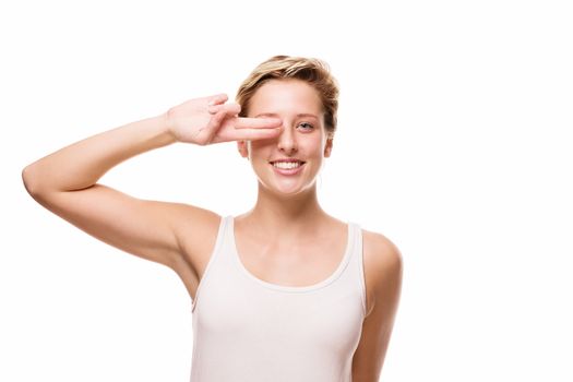 laughing blonde woman holding two fingers at her eye on white background