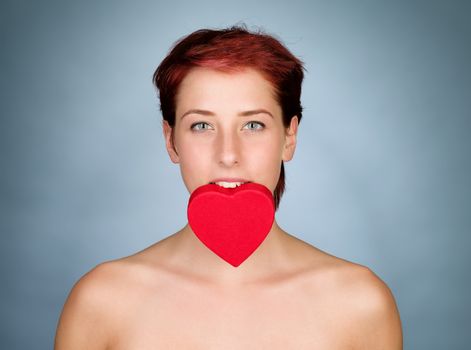 redhead woman holding a red heart with her mouth