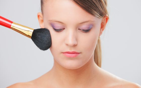 Cropped view of a young woman having blusher applied to her cheeks 