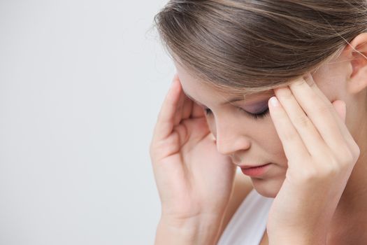 Close up headshot of a beauty rubbing at her temples to relieve a headache