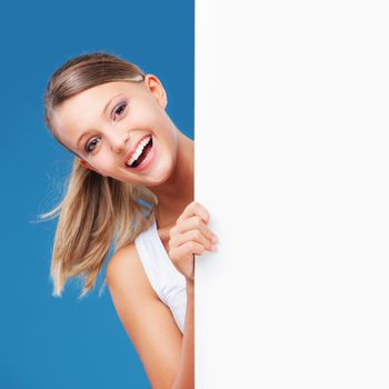 Happy girl looking at the camera from behind a large blank placard