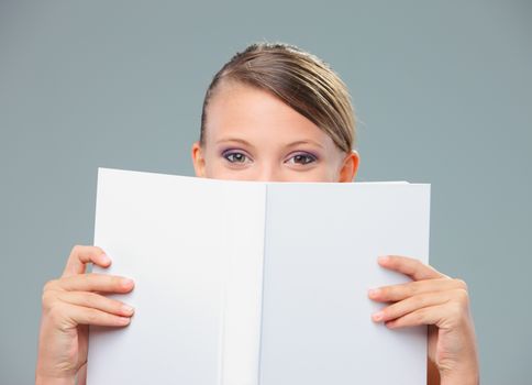 Beautiful young woman hiding herself behind a book