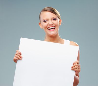 Happy blonde girl holding up a blank banner, copy space