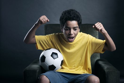 Happy young boy waching a soccer match on tv