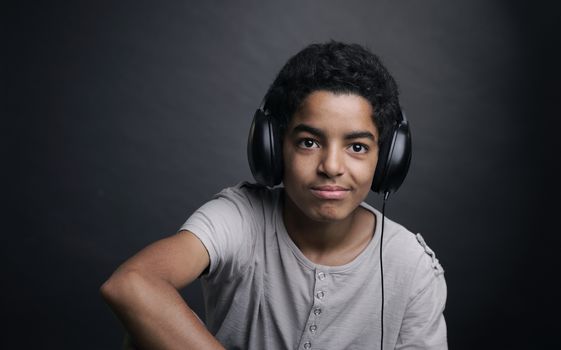 Portrait of african teenager listening music with headphones.