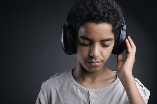 Portrait of african teenager listening music with headphones.