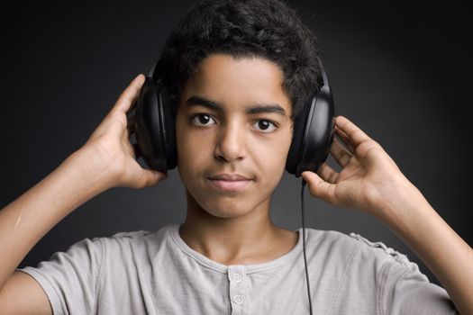 Portrait of african teenager listening music with headphones.