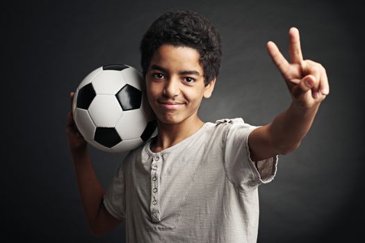 Portrait of young boy with a soccer ball signing victory