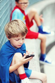 A child superhero playing with a smartphone