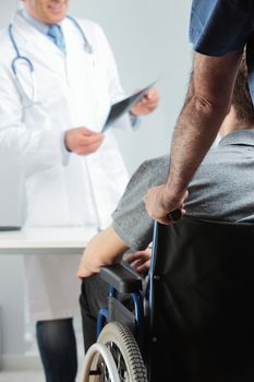 Young man on wheelchair meeting orthopedic doctor