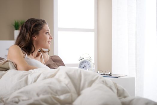 Young woman smiling while lying in bed 