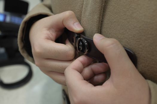 Close up of a pair of hands tightening a belt buckle