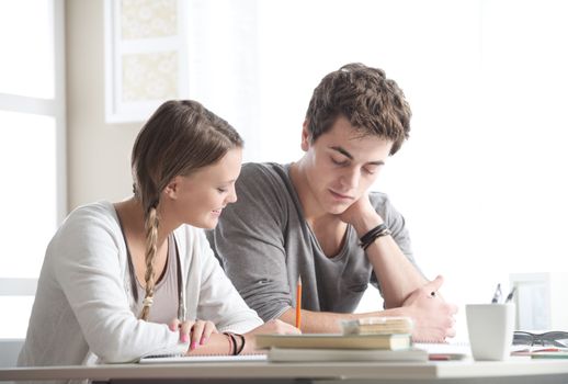 Teen boy and girl sitting together and studying 