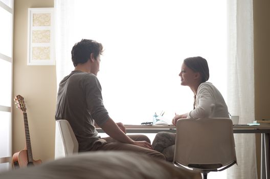 Teen boy and girl sitting together and studying at home