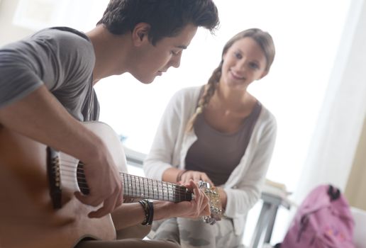 Young handsome man playing guitar for his girlfriend