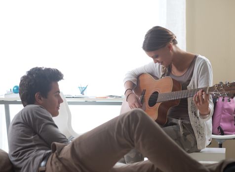 Beautiful girl playing guitar for her boyfriend at home 