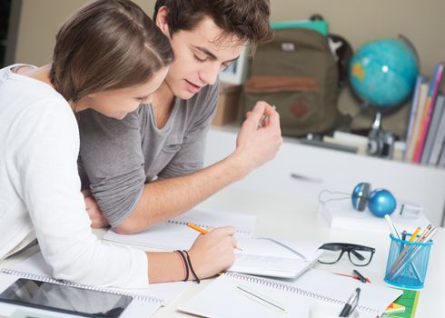 Teen boy and girl sitting together and studying 