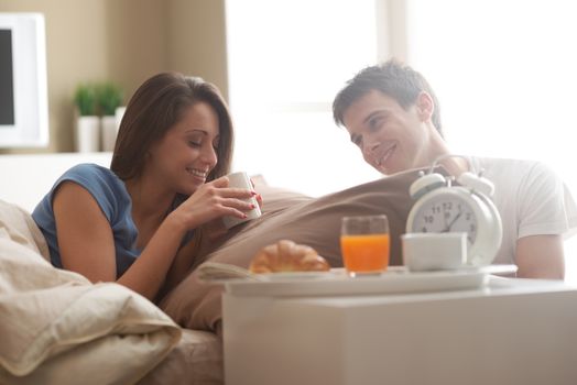 Beautiful smiling young couple having breakfast in bed