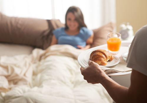 Hand holding breakfast tray to a happy relaxed woman in bed 