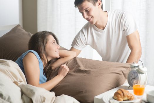 Beautiful smiling young couple having breakfast in bed