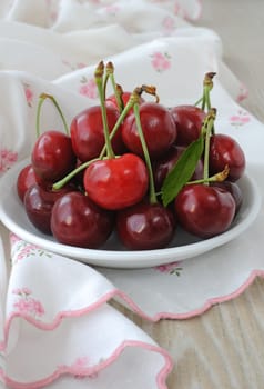 plate of ripe cherries on the table with a napkin