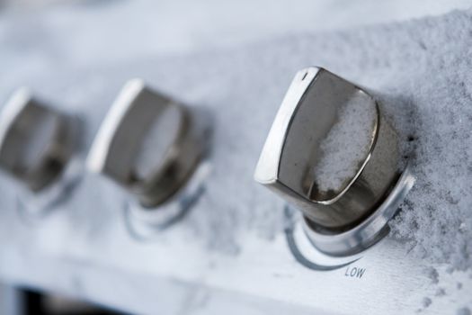 knob to control the flame on a BBQ covered in snow signaling the coming of winter