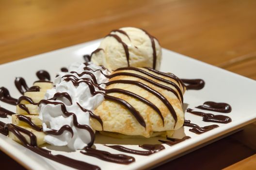 Crepes with banana , chocolate sauce  served with whipping cream and vanilla ice cream