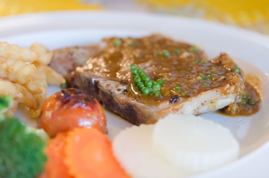 close up  beef  steak with green peppercorn sauce served with chips and vegetable
