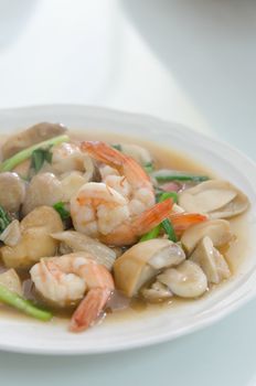 stir fried shrimp and mushroom with vegetable on white dish