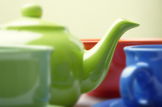 Close-up photo of the fragment of tea service consisting of teapot and cups. Natural color. Shallow depth of field added by the lens for natural view