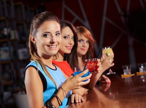 Three young women having a drink in a night club 