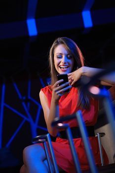 Young beautiful woman using a smartphone in a nightclub