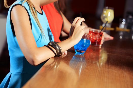 Drinking a blue cocktail at nightclub, hands close up